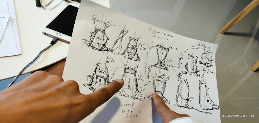 Drawing backpack d thumbnails with ballpoint pen discussion around ideas