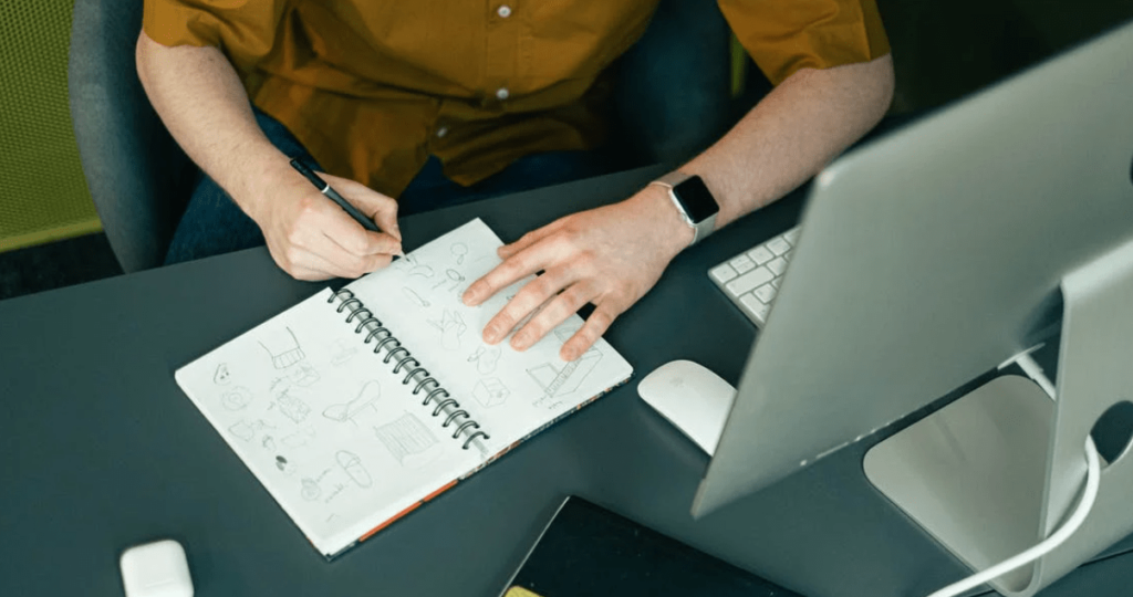 Man doodling ideas on notebook