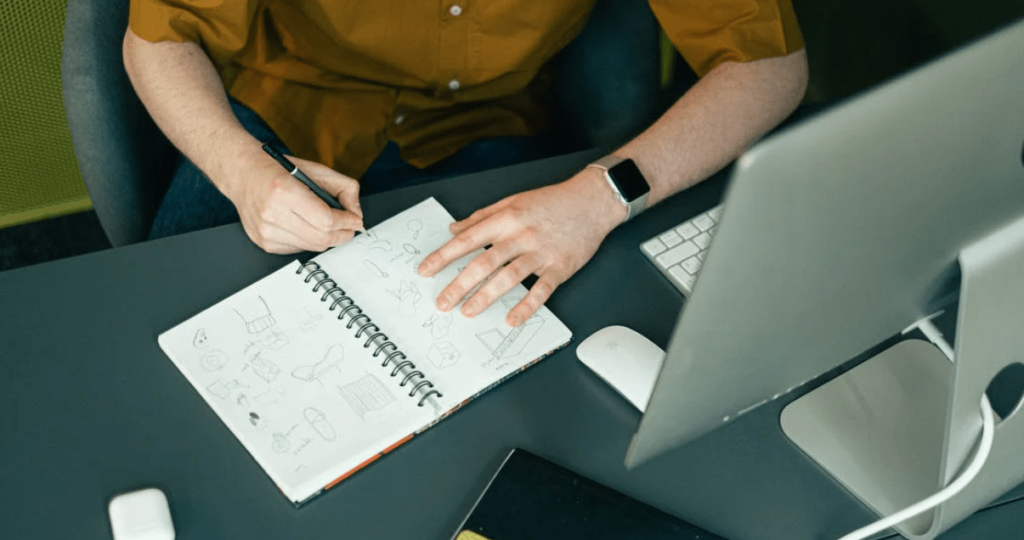 Man doodling ideas on notebook
